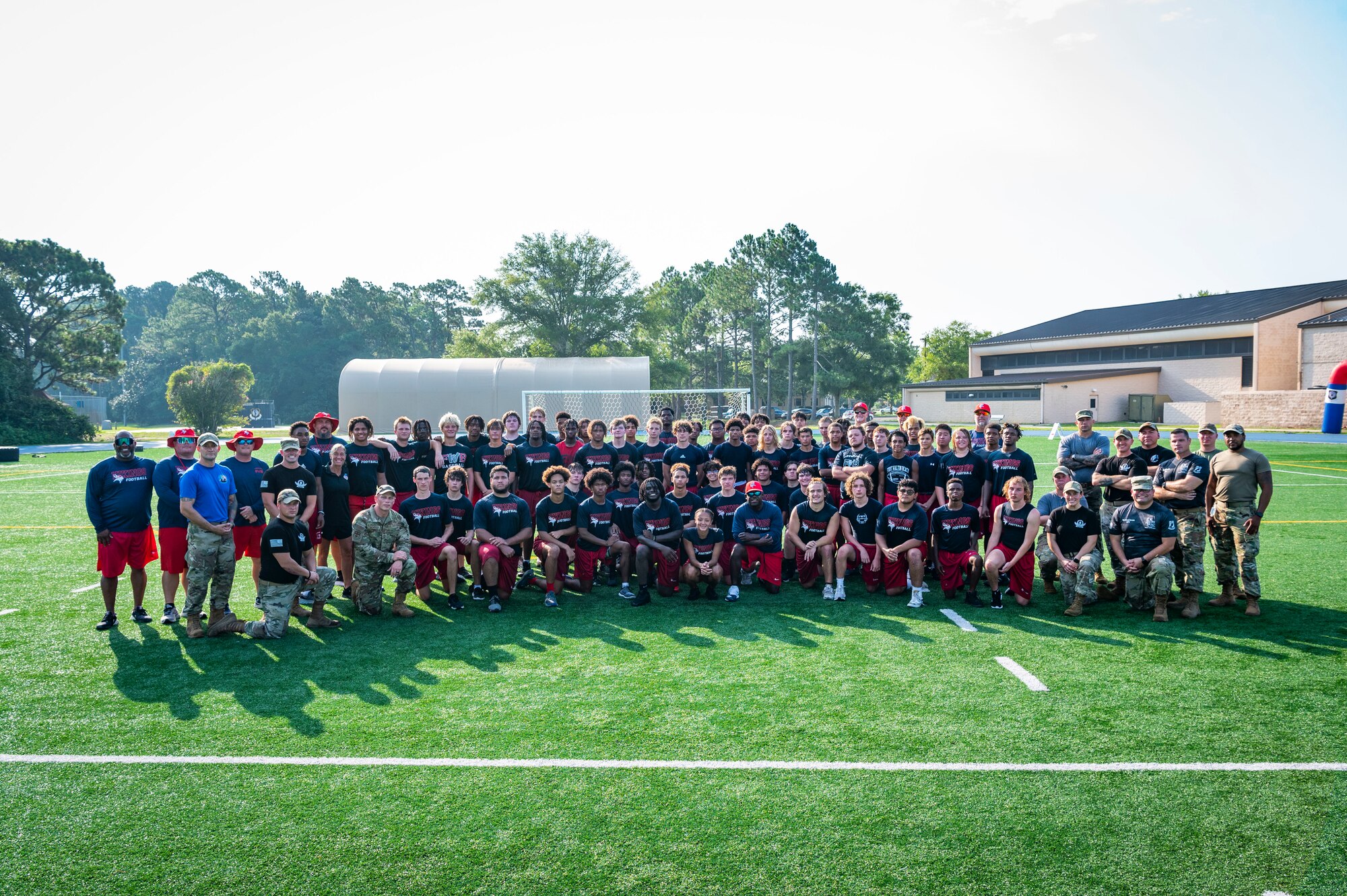 Air Commandos and members of the Fort Walton Beach High School Vikings football team pose for a photo during Air Commando Youth Athletic Camp at Hurlburt Field, Florida, July 19, 2023.