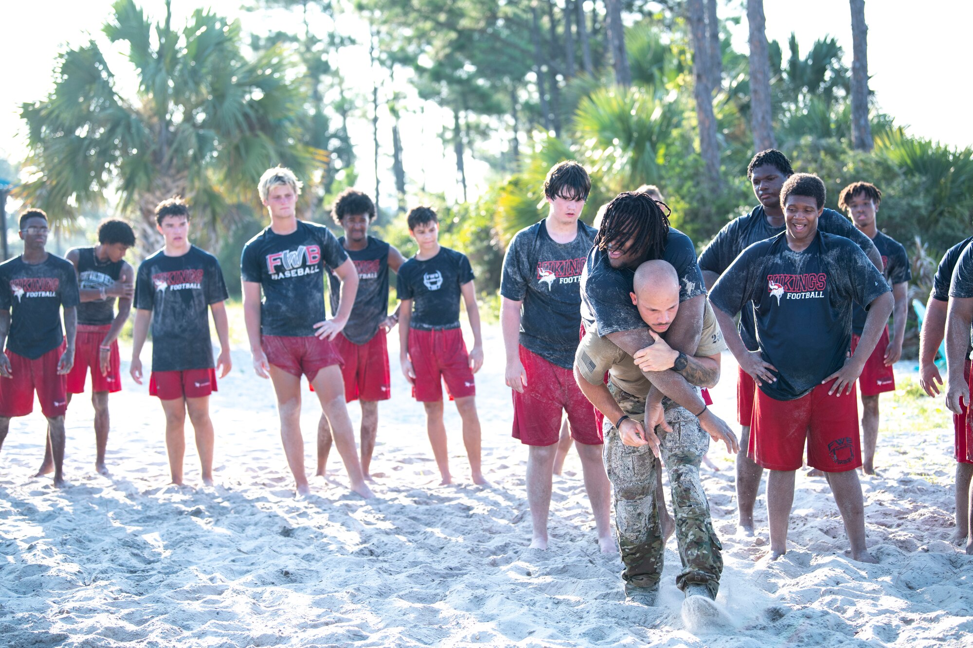 U.S. Air Force Tech. Sgt. Joseph Lowe, 371st Special Operations Combat Training Squadron DAGRE course chief, demonstrates a carrying technique for members of the Fort Walton Beach High School Vikings football team during Air Commando Youth Athletic Camp at Hurlburt Field, Florida, July 26, 2023.