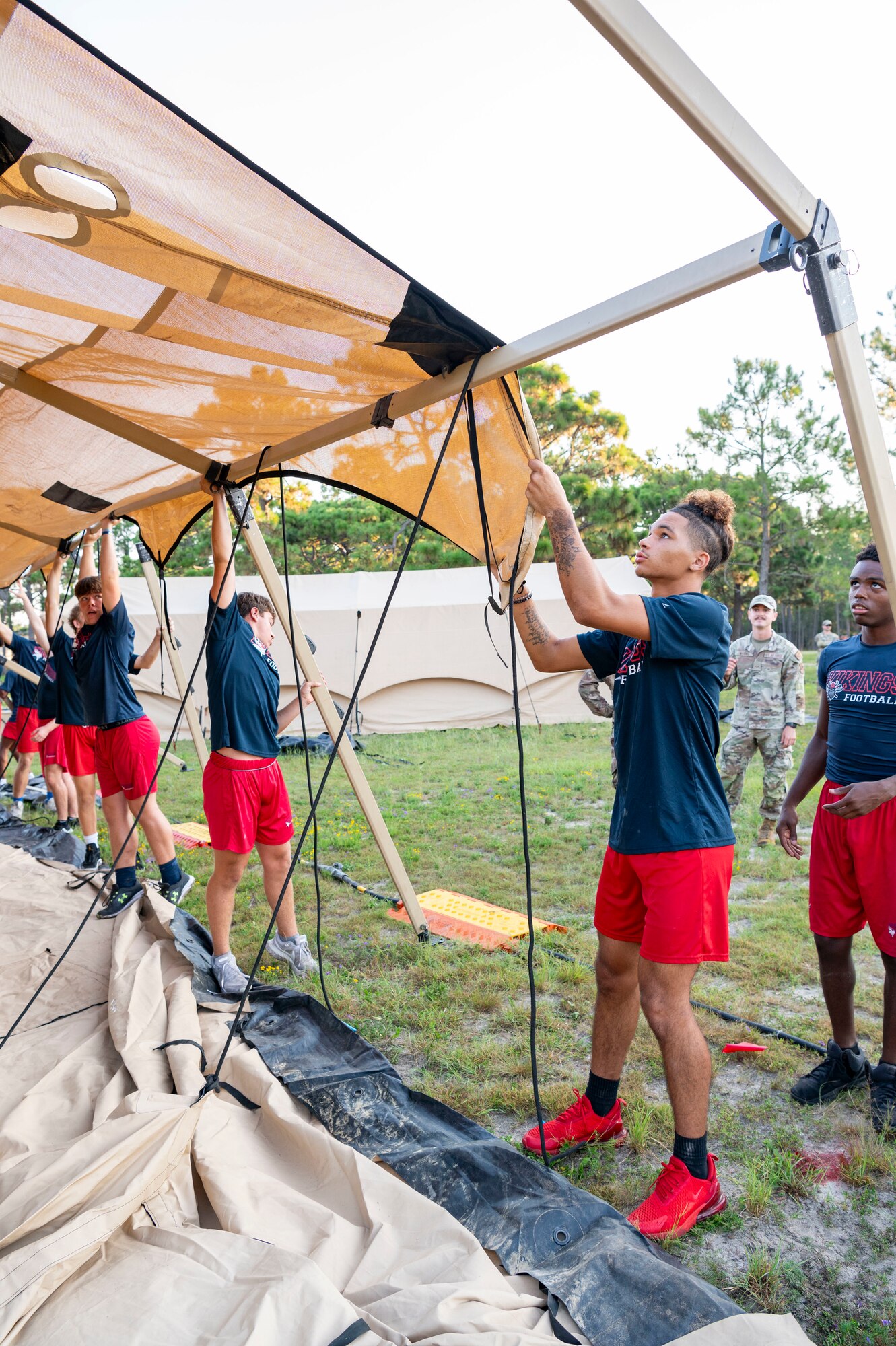 Members of the Fort Walton Beach High School Vikings football team build military tents during Air Commando Youth Athletic Camp at Hurlburt Field, Florida, Aug. 2, 2023