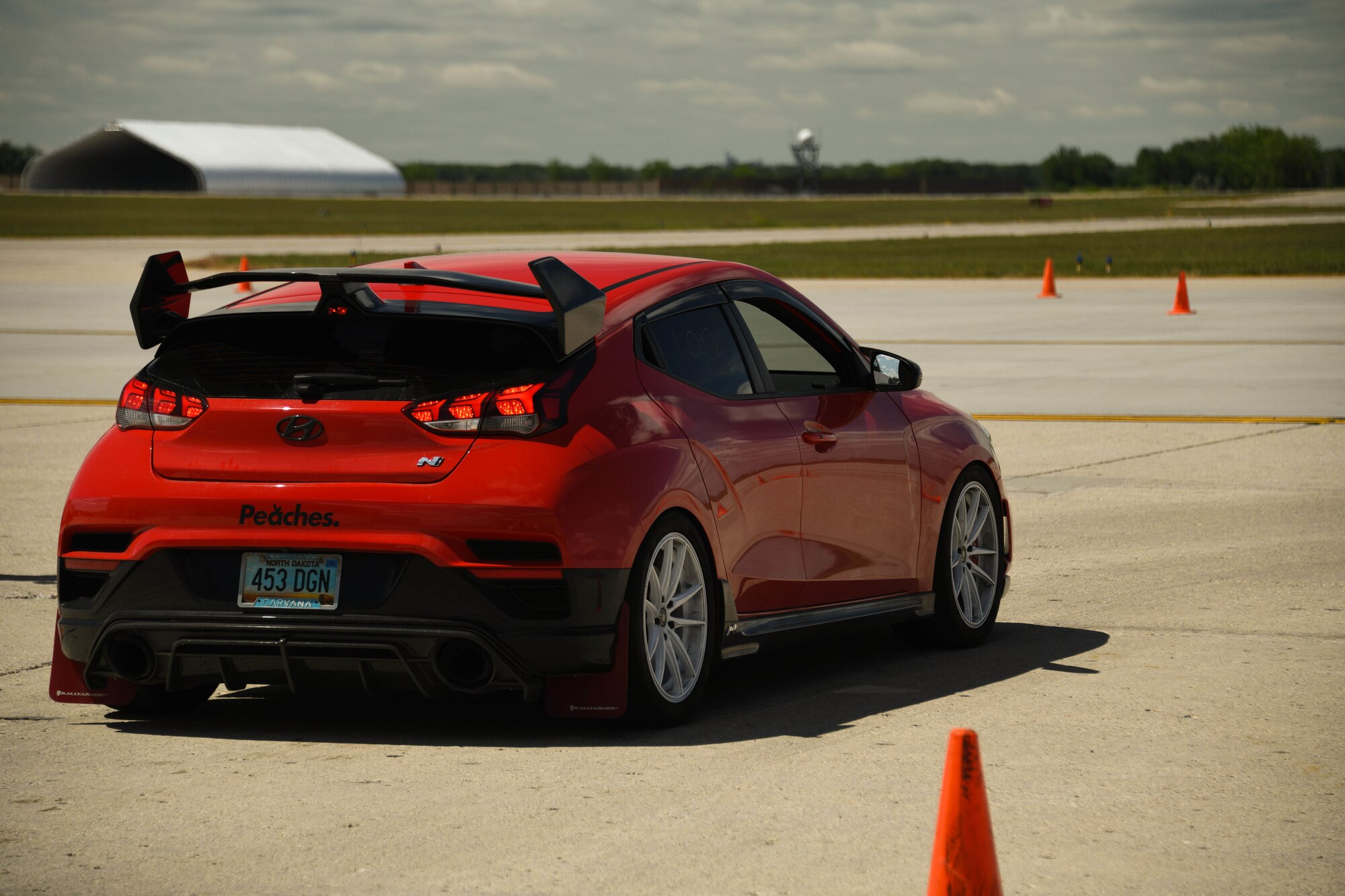 a red car is stopped on a concrete pad.