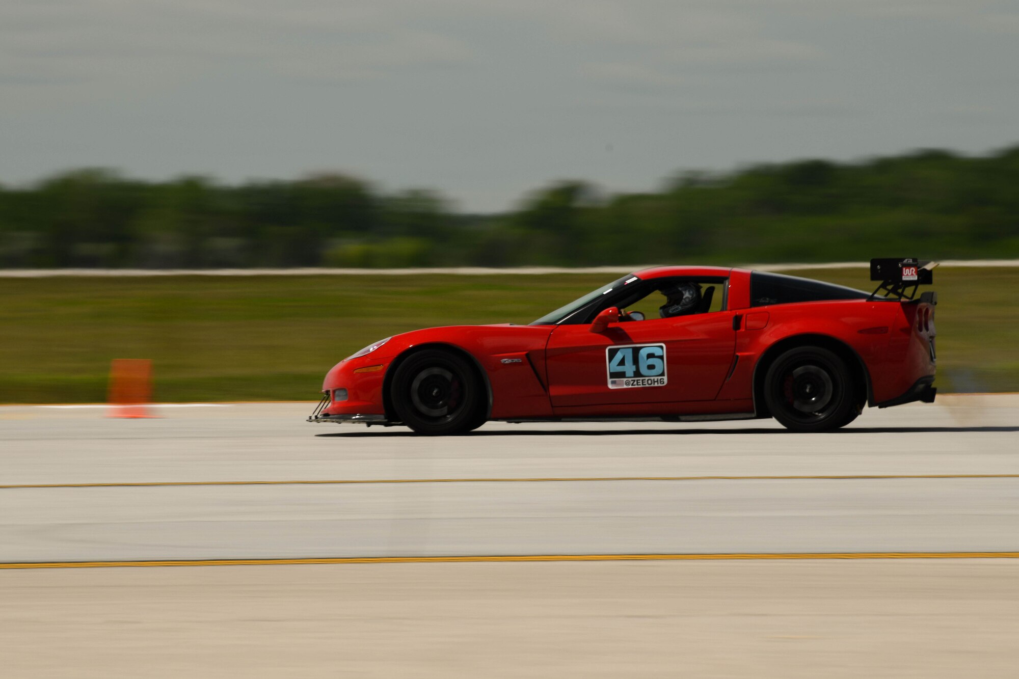 A red car flies down an airfield.