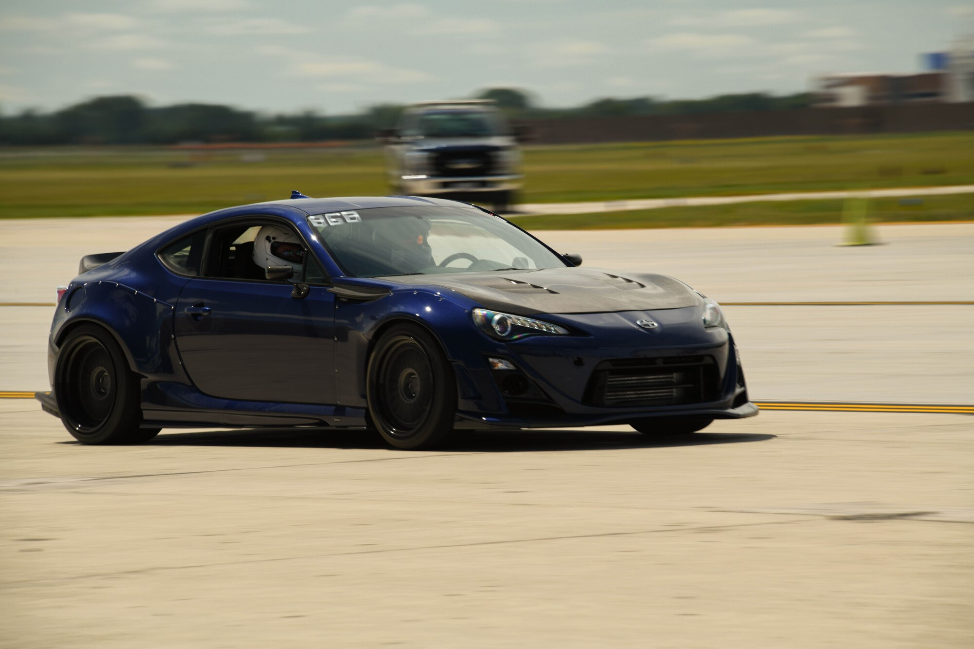 A dark blue car races down an airfield.