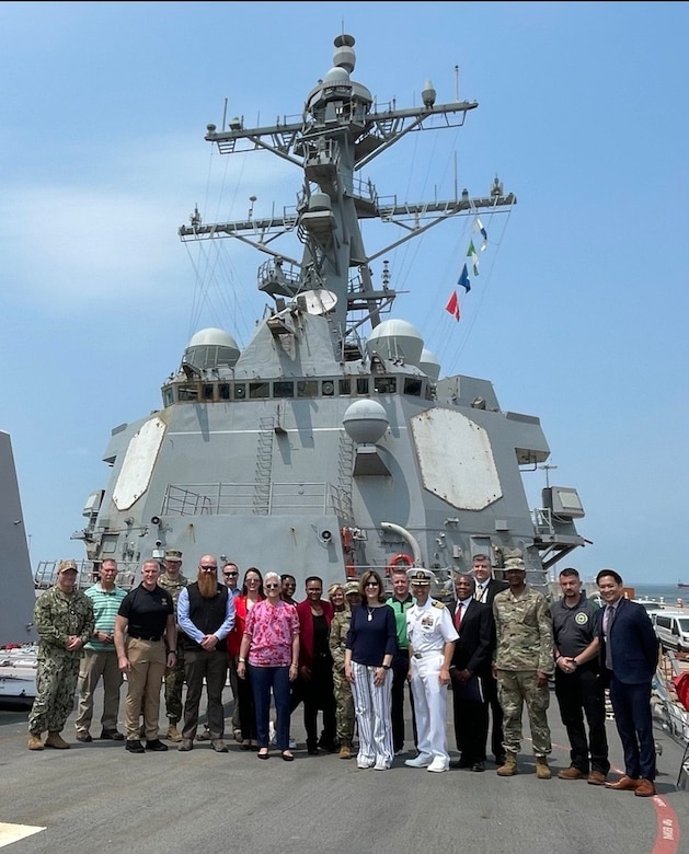 DOD Leaders stand on a ship deck on a sunny day.