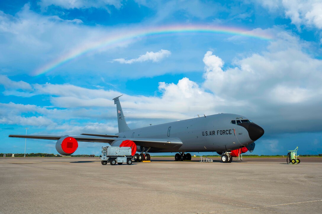 A rainbow shines above a parked aircraft.