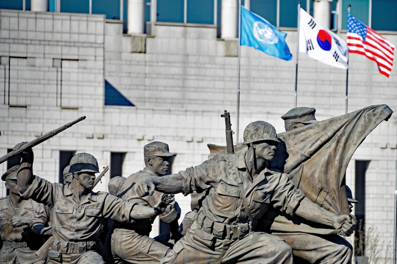 A statue depicts armed service members on the move.