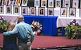 Two people embrace as they look at photos of coworkers who have passed away.