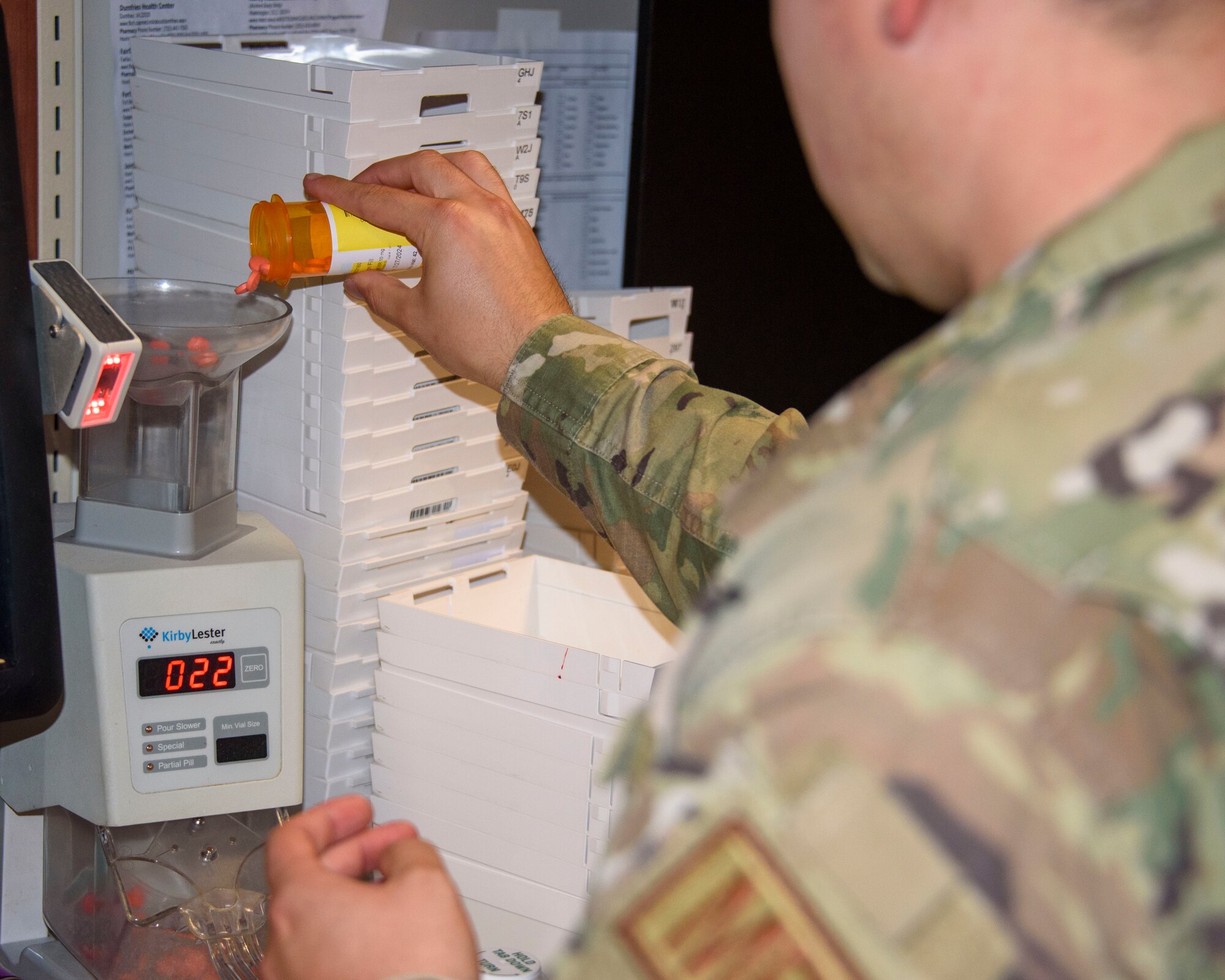A man in uniform fills a machine with medicine.