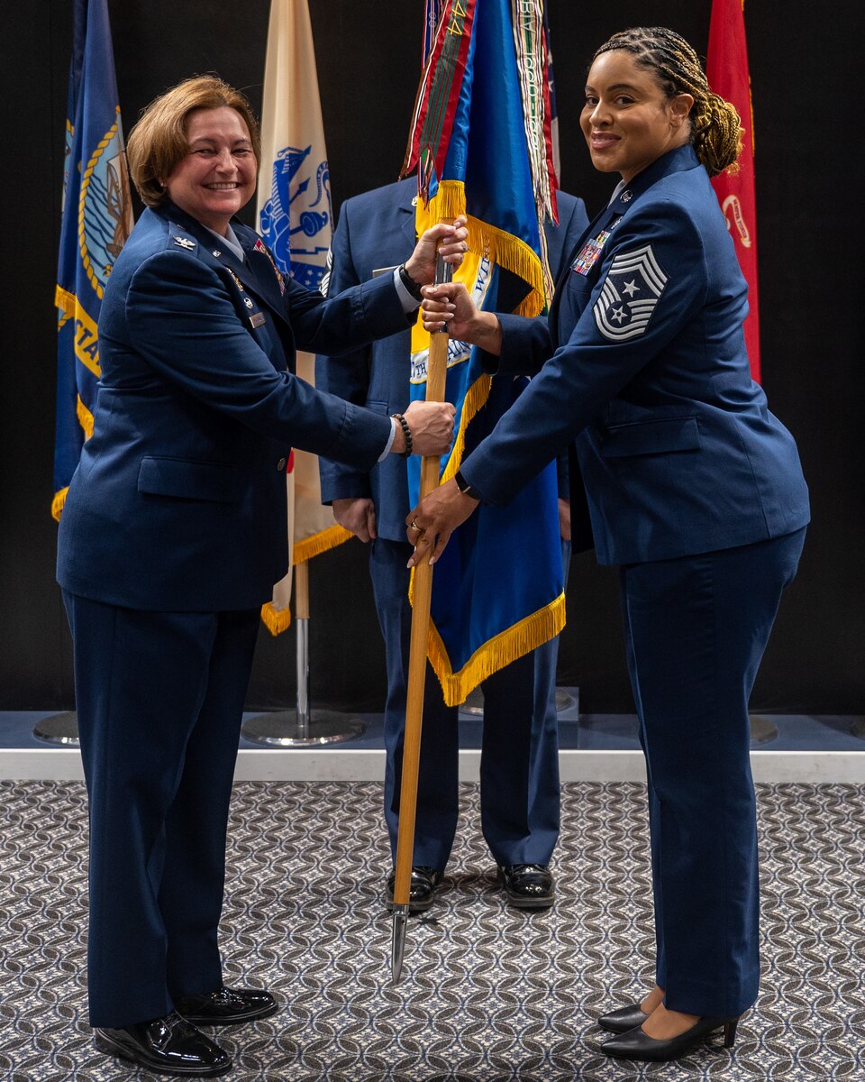 U.S. Air Force Col. Angelina Maguinness (left), 17th Training Wing commander, passes the guidon to Chief Master Sgt. Khamillia Washington (right), 17th Training Wing command chief, during an Assumption of Responsibility Ceremony at Goodfellow Air Force Base, Texas, July 24, 2023. Washington’s duties as the command chief of the wing include advising the commander on all matters related to the enlisted force. (U.S. Air Force photo by Airman 1st Class Evelyn D'Errico)