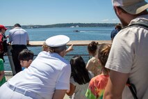 230801-N-YF131-1262 SEATTLE (Aug. 1, 2023) Chief Mass Communication Specialist Gretchen Albrecht, from Chino Hills, Calif., points ships out to civilians from Pier 62 during Seattle Fleet Week, Aug. 1, 2023. Seattle Fleet Week is a time-honored celebration of the sea services and provides an opportunity for the citizens of Washington to meet Sailors, Marines and Coast Guardsmen, as well as witness firsthand the latest capabilities of today’s U.S. and Canadian maritime services. (U.S. Navy photo by Mass Communication Specialist 2nd Class Madison Cassidy)