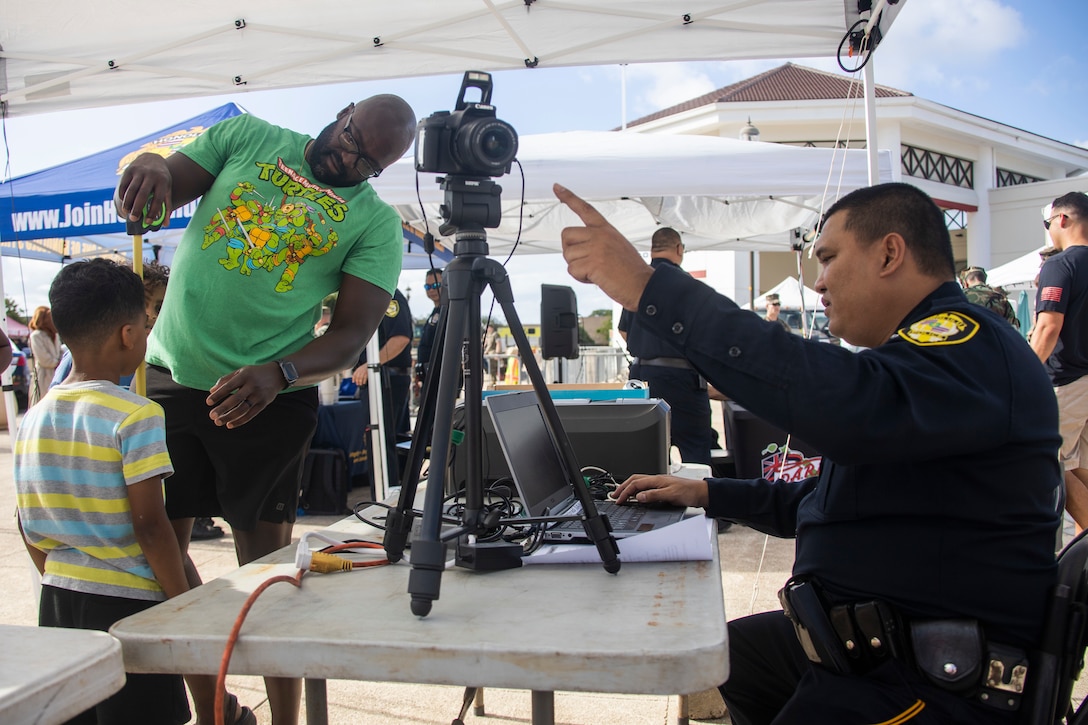 Marine Corps Base Hawaii community members interact with a police officer with the Honolulu Police Department during a National Night Out event, MCBH, Aug. 1, 2023. National Night Out is an annual community-building campaign that enhances the relationship between law enforcement, first and emergency responders, and the community they serve. (U.S. Marine Corps photo by Sgt. Julian Elliott-Drouin)