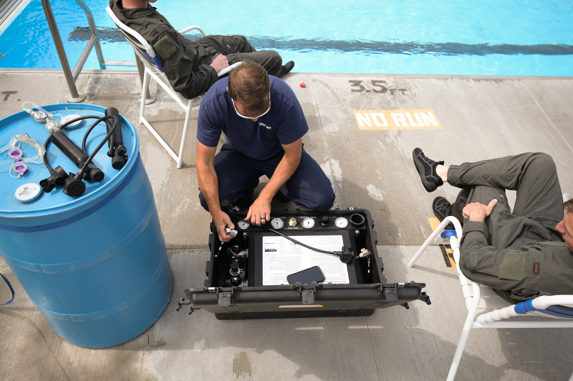 A man leans over a Pelican case to refill cannisters with oxygen.