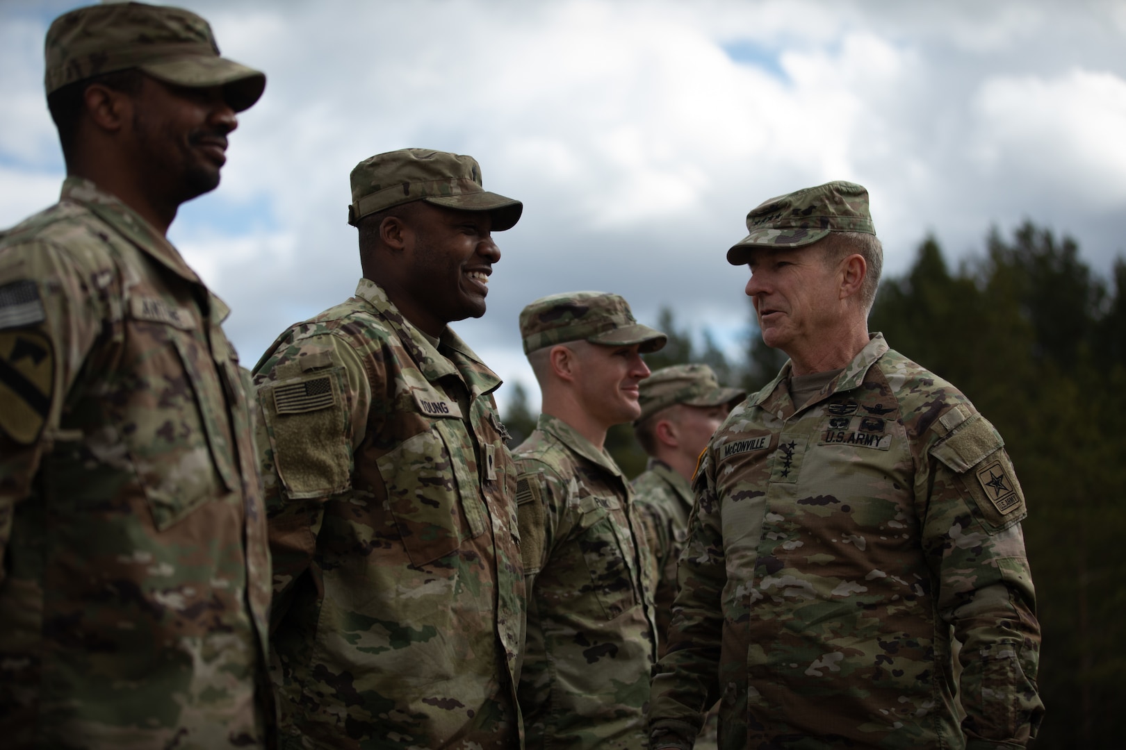 An older, male soldier smiles as he looks at a row of smiling soldiers.