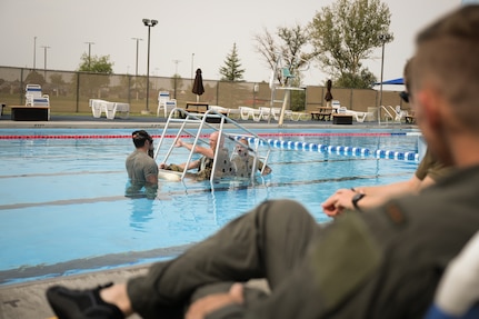 Three men practice water survival training in the base bool.