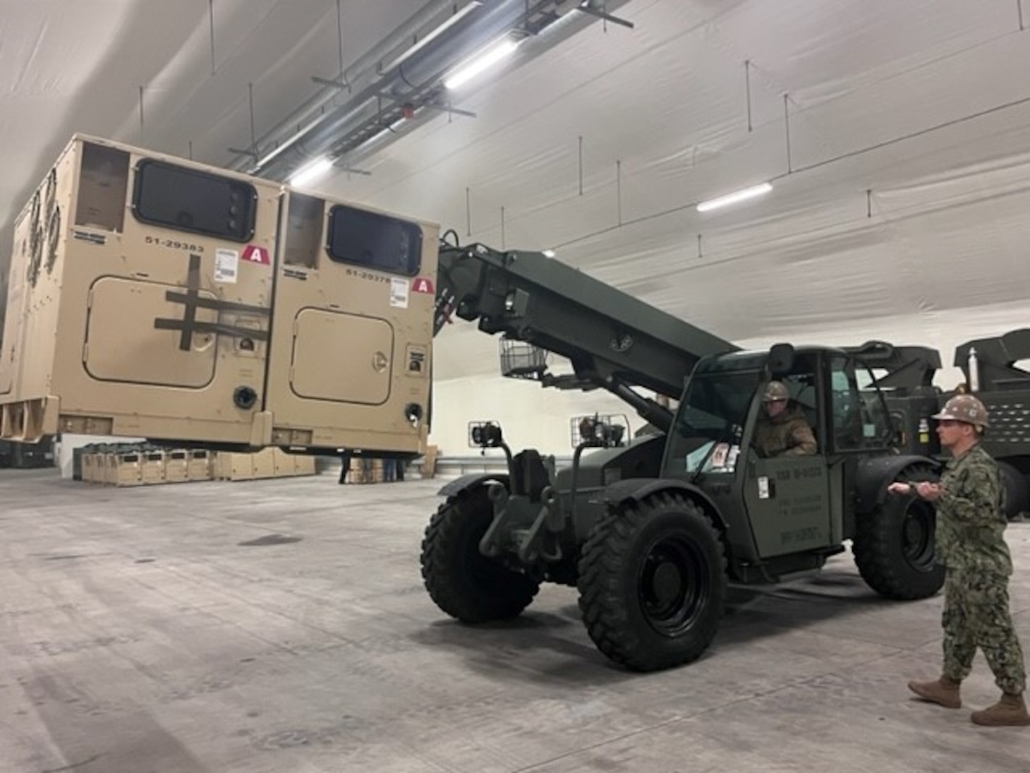 EOCA Stephen Cosby operates an 11K Rough Terrain Forklift to relocate a 60 kilowatt Advanced Medium Mobile Power System while EO2 Tyler Campbell ground guides.