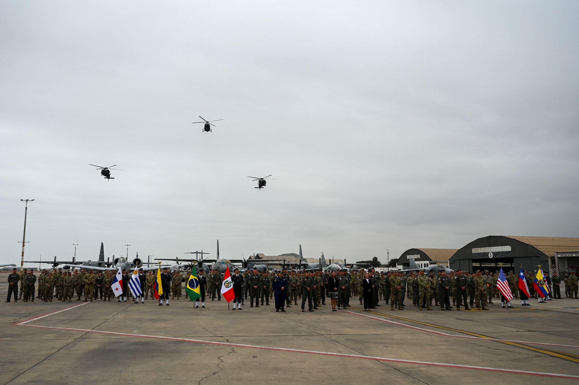 A combined formation of Peruvian and U.S. Air Force Airmen stand on the flight line at Lima in front of aircraft representing both countries.