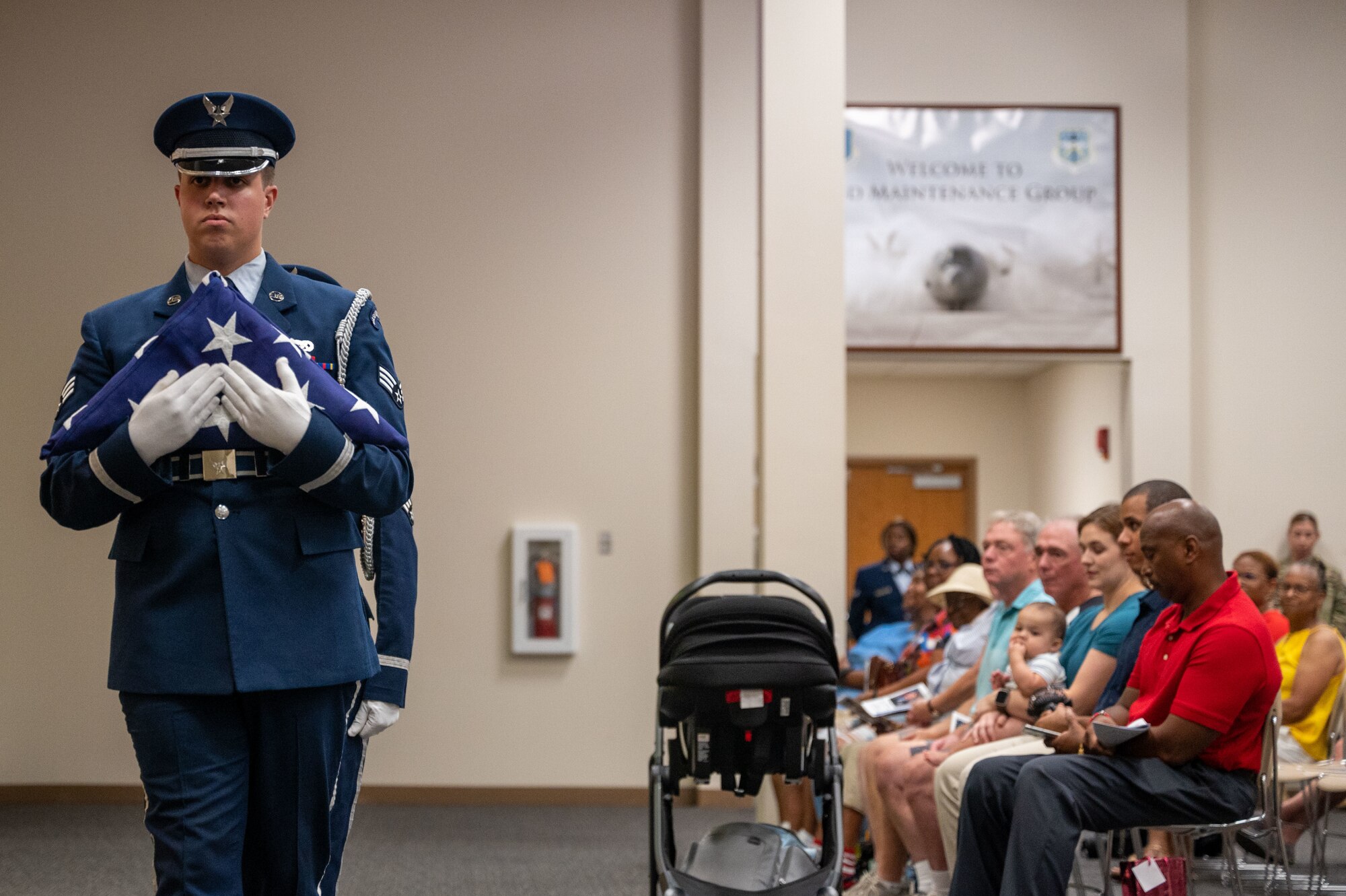 An Airman in service dress clutches a folded U.S. flag to his chest.