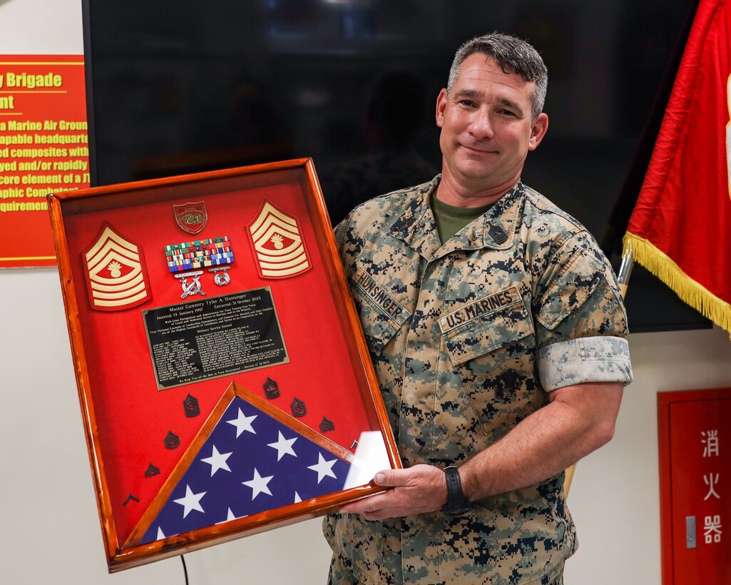 U.S. Marine Master Gunnery Sgt. Tyler Hunsinger, operations chief, 3rd Marine Expeditionary Brigade, III Marine Expeditionary Force, and Task Force 76/3, is presented with a going-away gift from the Marines and Sailors of 3rd MEB at his going-away ceremony on Camp Courtney, Okinawa, Japan, June 30, 2023. Hunsinger, an infantry Marine by trade,  is retiring after 25 years of service.(U.S. Marine Corps photos by 1st Lt. Isabel Izquierdo)