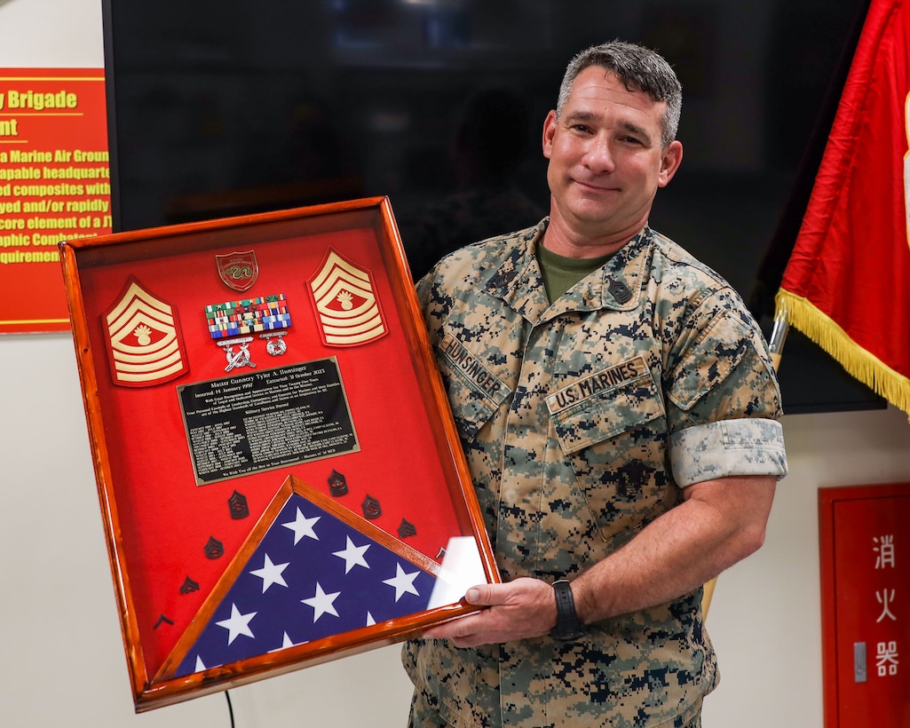 U.S. Marine Master Gunnery Sgt. Tyler Hunsinger, operations chief, 3rd Marine Expeditionary Brigade, III Marine Expeditionary Force, and Task Force 76/3, is presented with a going-away gift from the Marines and Sailors of 3rd MEB at his going-away ceremony on Camp Courtney, Okinawa, Japan, June 30, 2023. Hunsinger, an infantry Marine by trade,  is retiring after 25 years of service.(U.S. Marine Corps photos by 1st Lt. Isabel Izquierdo)