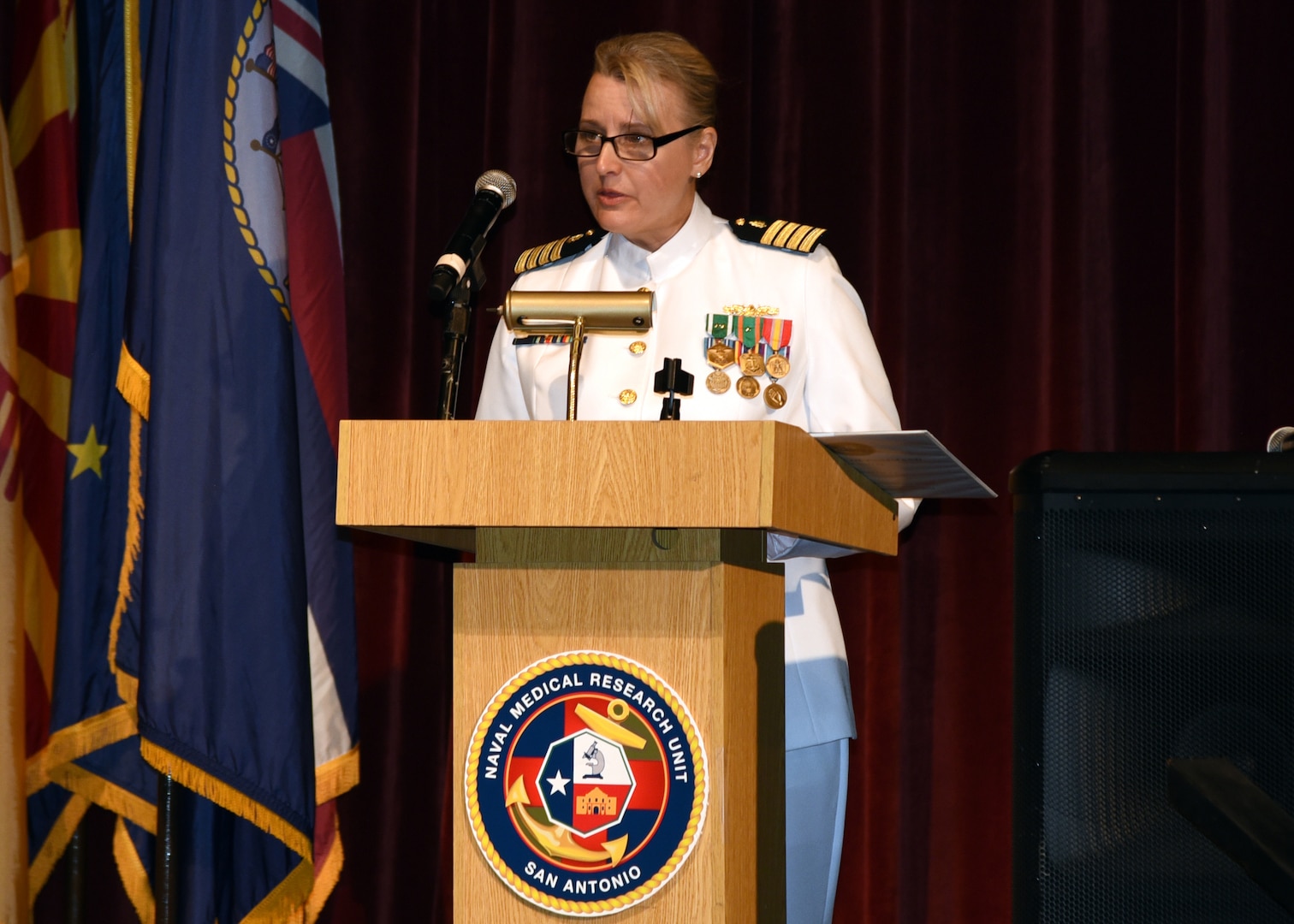 JOINT BASE SAN ANTONIO-FORT SAM HOUSTON – (Aug. 4, 2023) – Capt. Jennifer Buechel, Nurse Corps, of Woodhaven, Mich., speaks to Sailors, Soldiers, and guests after assuming command of Naval Medical Research Unit (NAMRU) San Antonio from Capt. Gerald DeLong, Medical Service Corps (MSC), of Belvidere, Ill., during a Change of Command Ceremony held at the Fort Sam Houston Theatre. Capt. William Deniston, Medical Service Corps, commander, Naval Medical Research Command (NMRC) presided over the ceremony and Capt. Robert Hawkins, director, J3/5/7, Defense Health Agency (DHA) and director, U.S. Navy Nurse Corps, served as the guest speaker. NAMRU San Antonio’s mission is to conduct gap driven combat casualty care, craniofacial, and directed energy research to improve survival, operational readiness, and safety of Department of Defense (DoD) personnel engaged in routine and expeditionary operations. It is one of the leading research and development laboratories for the U.S. Navy under the DoD and is one of eight subordinate research commands in the global network of laboratories operating under NMRC in Silver Spring, Md. (U.S. Navy photo by Burrell Parmer, NAMRU San Antonio Public Affairs/Released)