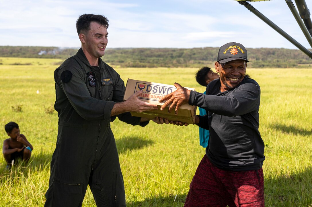 U.S. Marine Corps Cpl. Daniel Lauer, a crew chief with Marine Medium Tiltrotor Squadron 163, Marine Aircraft Group 16, 3rd Marine Aircraft Wing passes emergency relief supplies to a Filipino citizen in support of relief efforts in the wake of Typhoon Egay, international name Typhoon Doksuri, on Fuga Island, Philippines, Aug. 3, 2023. At the request of the Armed Forces of the Philippines, U.S. Marines are providing relief and lifesaving capabilities to remote regions of the Philippines. The forward presence and ready posture of I Marine Expeditionary Force assets in the region facilitated rapid and effective response to crisis, demonstrating U.S. commitment to Allies and partners. During the three days of relief efforts, VMM-163 delivered approximately 64,000 pounds of food and water, provided by the Government of the Philippines, to remote, affected communities. Lauer is a Gurnee, Illinois native.