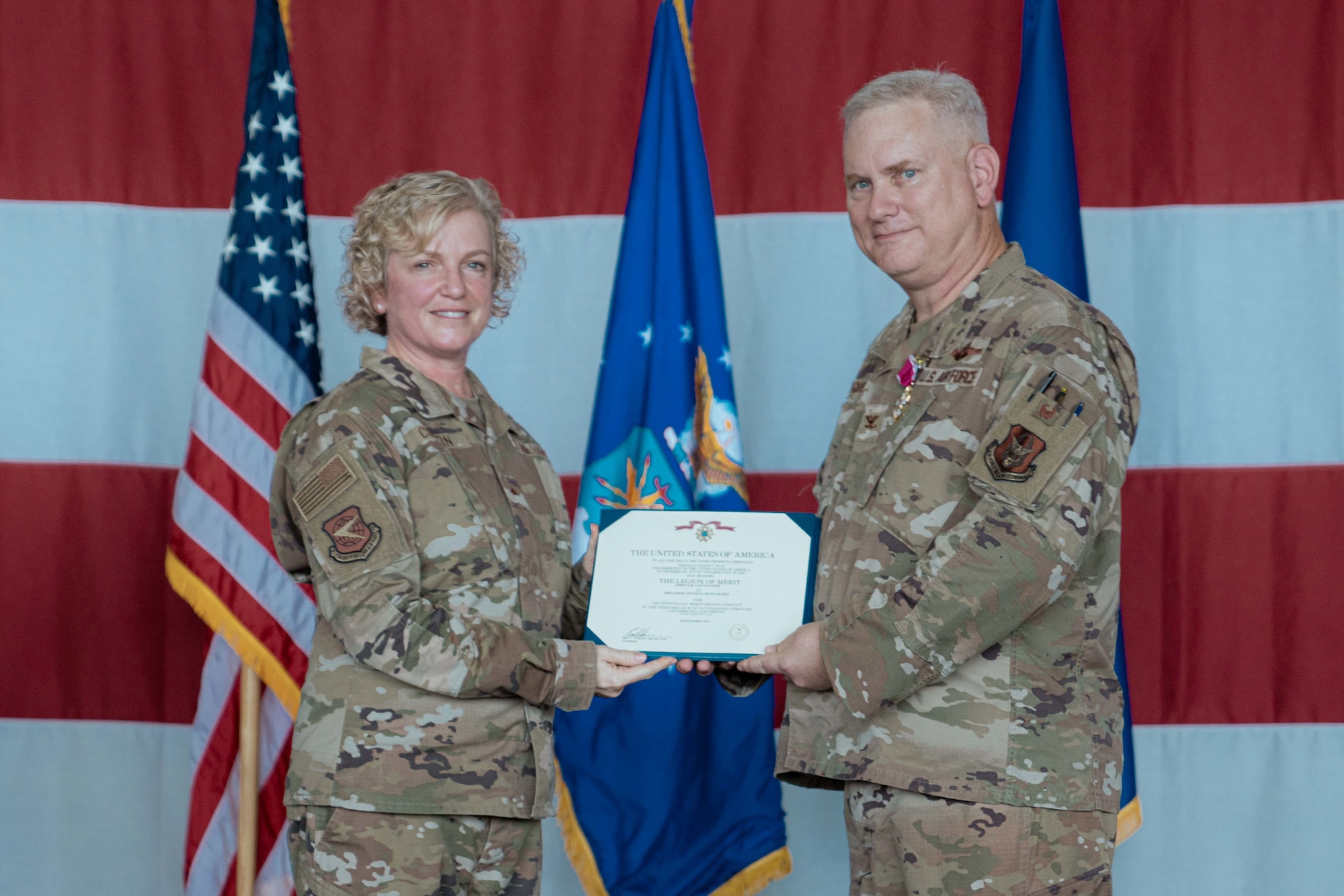 Brig. Gen. Melissa A. Coburn, 22nd Air Force commander, and Col. Carl Magnusson, outgoing 94th Airlift Wing commander, pose for a photo with Magnusson's Legion of Merit award.