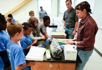 IMAGE: Kelly Morgan, a scientist in the Strategic and Computing Systems Department at Naval Surface Warfare Center Dahlgren Division, and Nicholas Giampetro, a student trainee in the Weapons Control and Integration Department, allow children at the Spotsylvania County Sheriff’s Office STEM Camp to shop for materials to build a boat July 31 at the Germanna Community College Fredericksburg Area Campus.