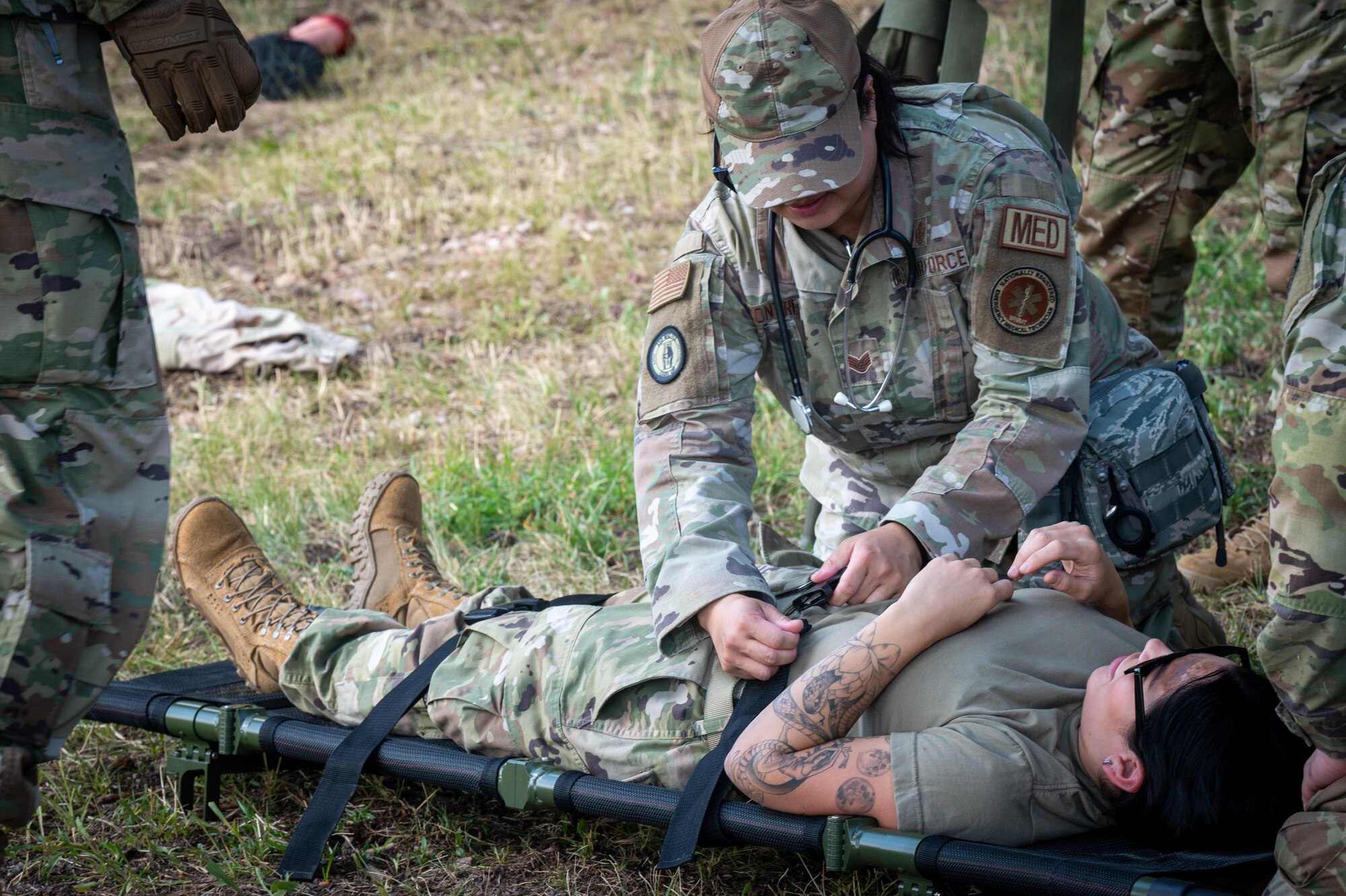 A person in military uniform attending to a injured person.