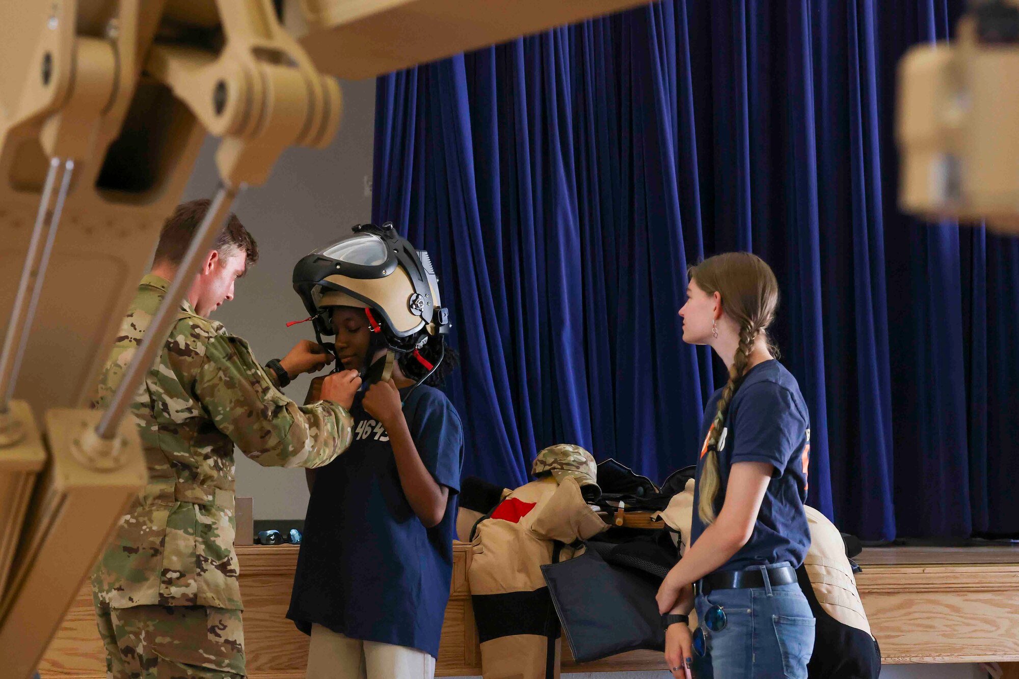 U.S. Air Force Staff Sgt. Connor Ely, 9th Civil Engineer Squadron explosive ordnance technician, shows Azalia Mutebi, a student with For Inspiration and Recognition of Science and Technology (FIRST), how to put on explosive ordnance disposal Personal Protective Equipment (PPE) during a base tour Aug. 3, 2023, at Beale Air Force Base, California.