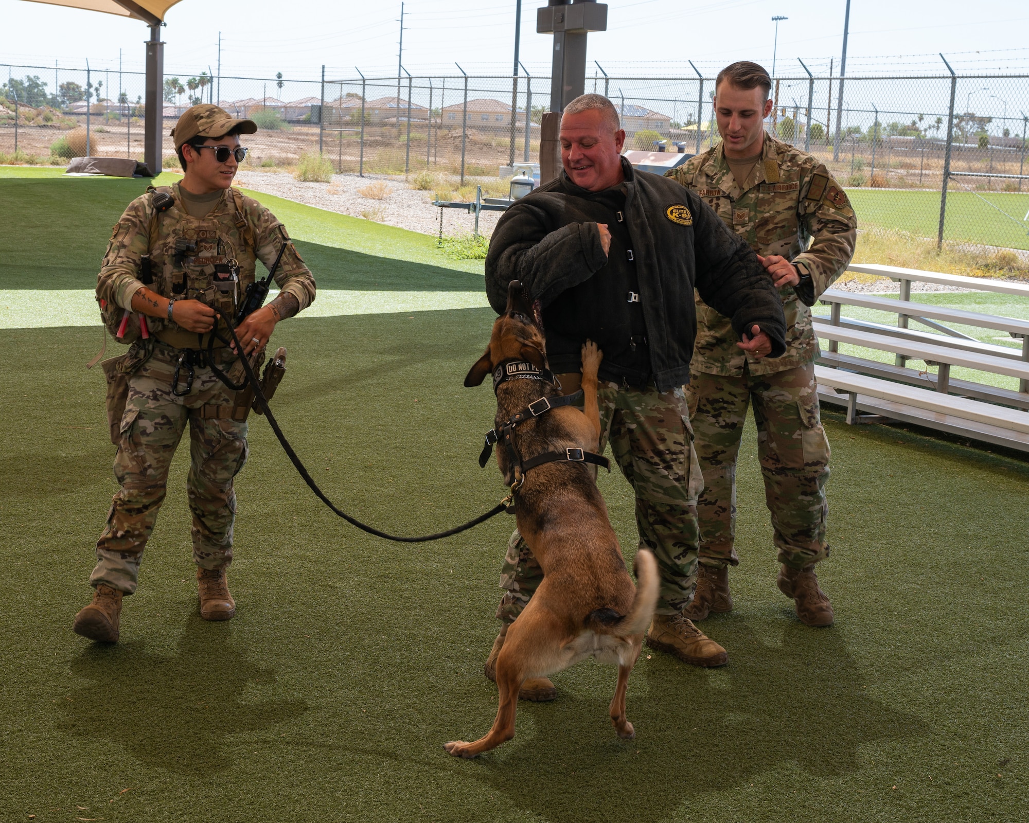 U.S. Air Force Chief Master Sgt. Justin Apticar, Nineteenth Air Force command chief, participates in a military working dog demonstration conducted by U.S. Air Force Staff Sgt. Elizabeth Pedroza and U.S. Air Force Staff Sgt. Dakota Farrow, 56th Security Forces Squadron MWD handlers, Aug. 1, 2023, at Luke Air Force Base, Arizona.