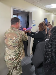 192nd Wing Commander and member of Kappa Epsilon Psi Military Sorority, Inc. cutting ribbon for doorway.