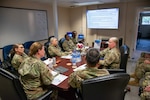 Airmen sit at a conference table for a meeting.