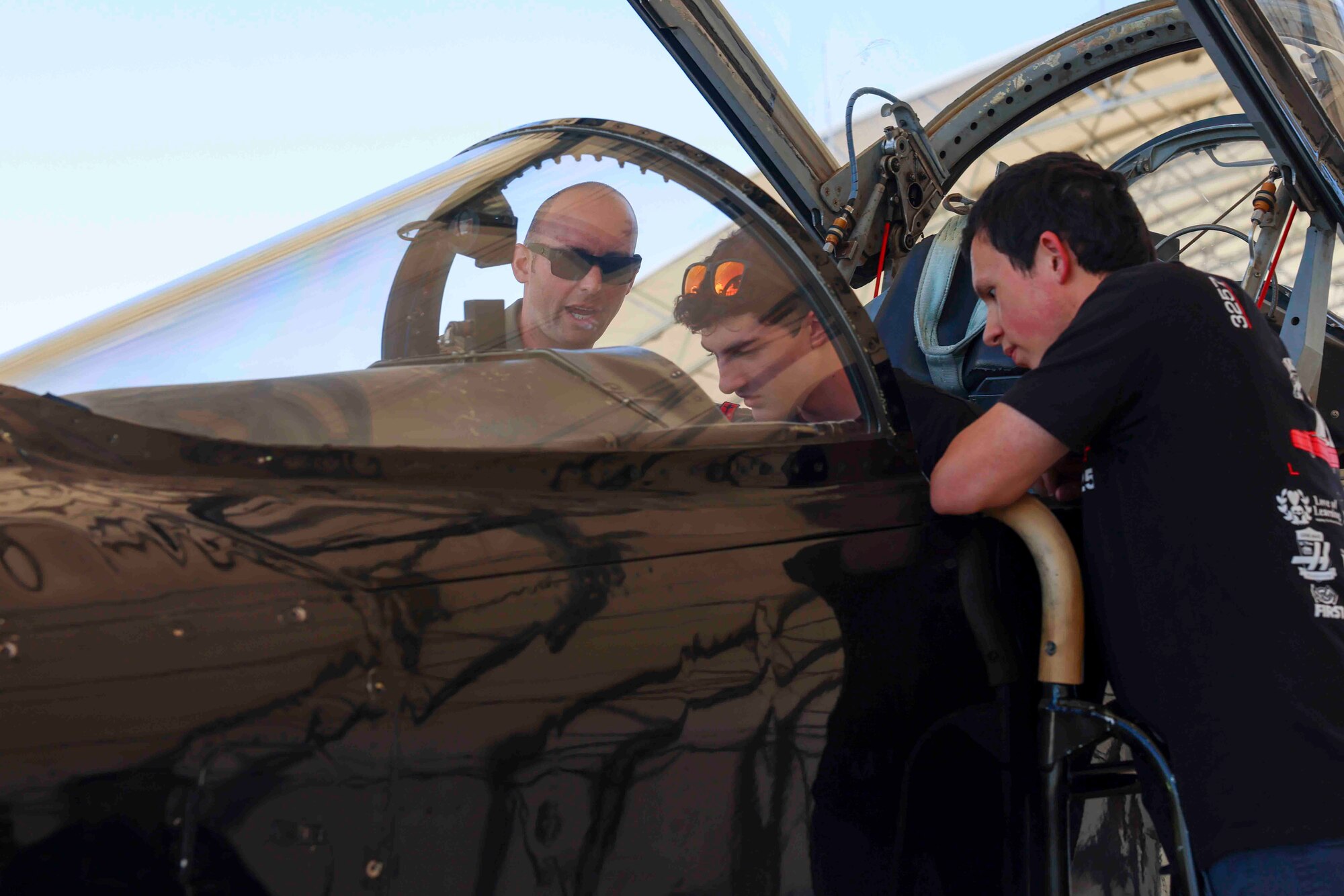 U.S. Air Force Lt. Col. Cole, 1st Reconnaissance Squadron pilot, shows Charles Hinky and Evan White, students with For Inspiration and Recognition of Science and Technology (FIRST), the various controls in the cockpit of a T-38 Talon during a base tour Aug. 3, 2023, at Beale Air Force Base, California.