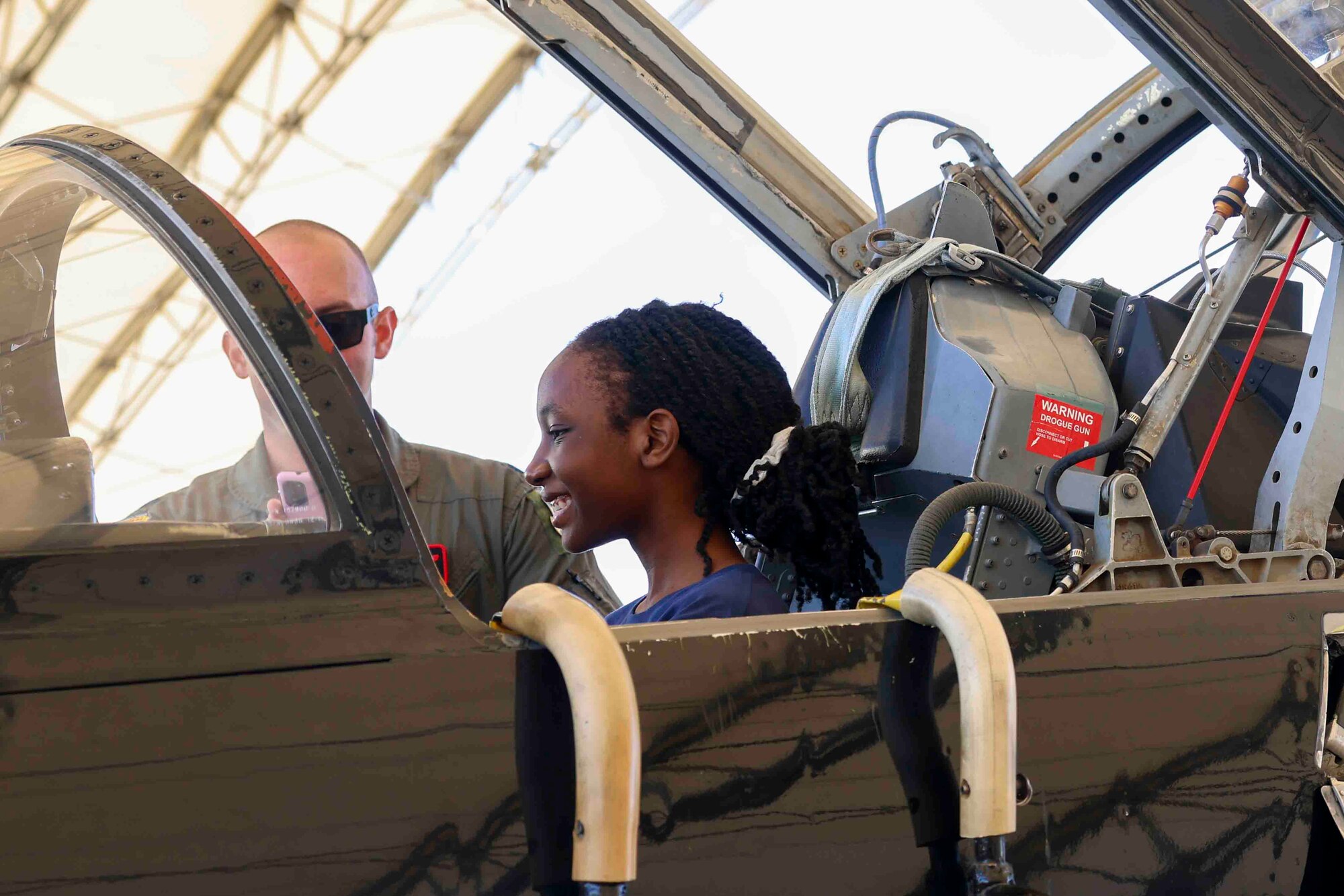 U.S. Air Force Lt. Col. Cole, 1st Reconnaissance Squadron pilot, shows Azalia Mutebi, a student with For Inspiration and Recognition of Science and Technology (FIRST), the various controls in the cockpit of a T-38 Talon during a base tour Aug. 3, 2023, at Beale Air Force Base, California.