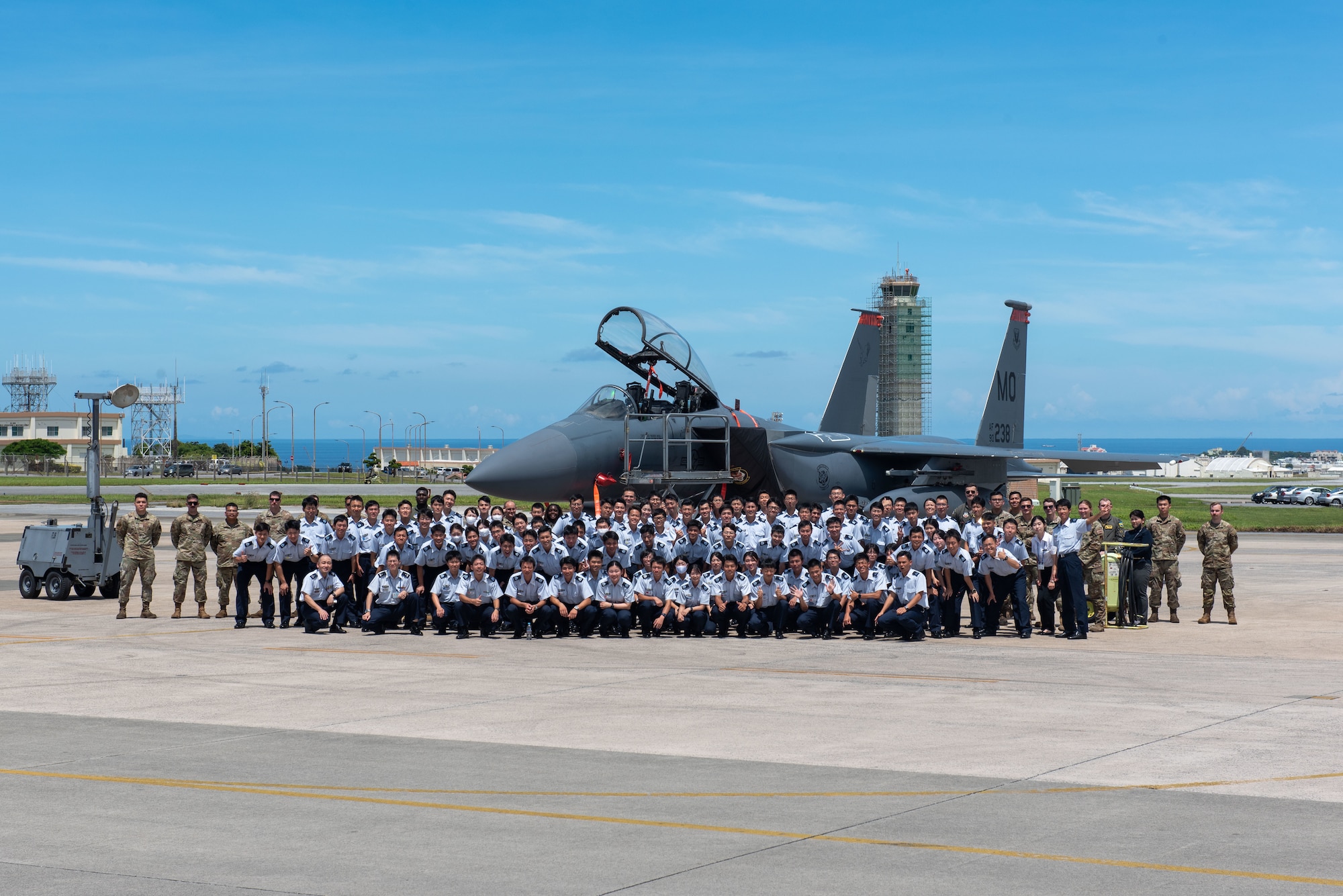 Japan Air Self-Defense Force cadets and U.S. Air Force Airmen pose for a group photo in front of an F-15E Strike Eagle