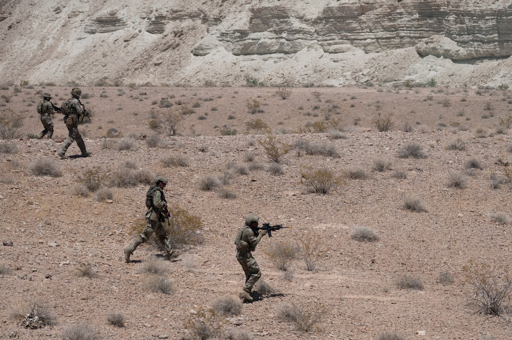 Four U.S. Airmen walk in a line during an air base defense rehearsal during exercise Red Flag 23-3 at Nellis AFB, Nevada, July 25, 2023. These defenders were establishing security for the forward operating site and contingency locations necessary to perform Agile Combat Employment. (U.S. Air Force photo by Master Sgt. Niles Bartram)