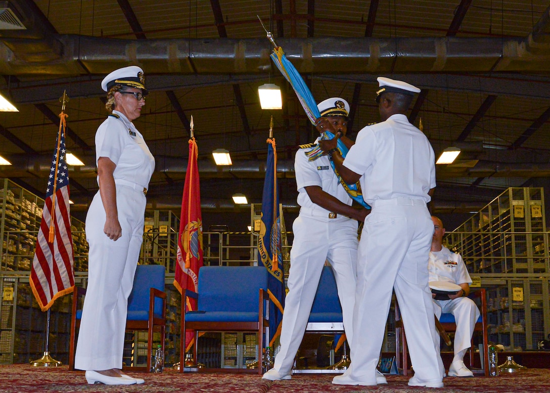 Navy officers pass the Defense Logistics Agency colors in a change of command ceremony.