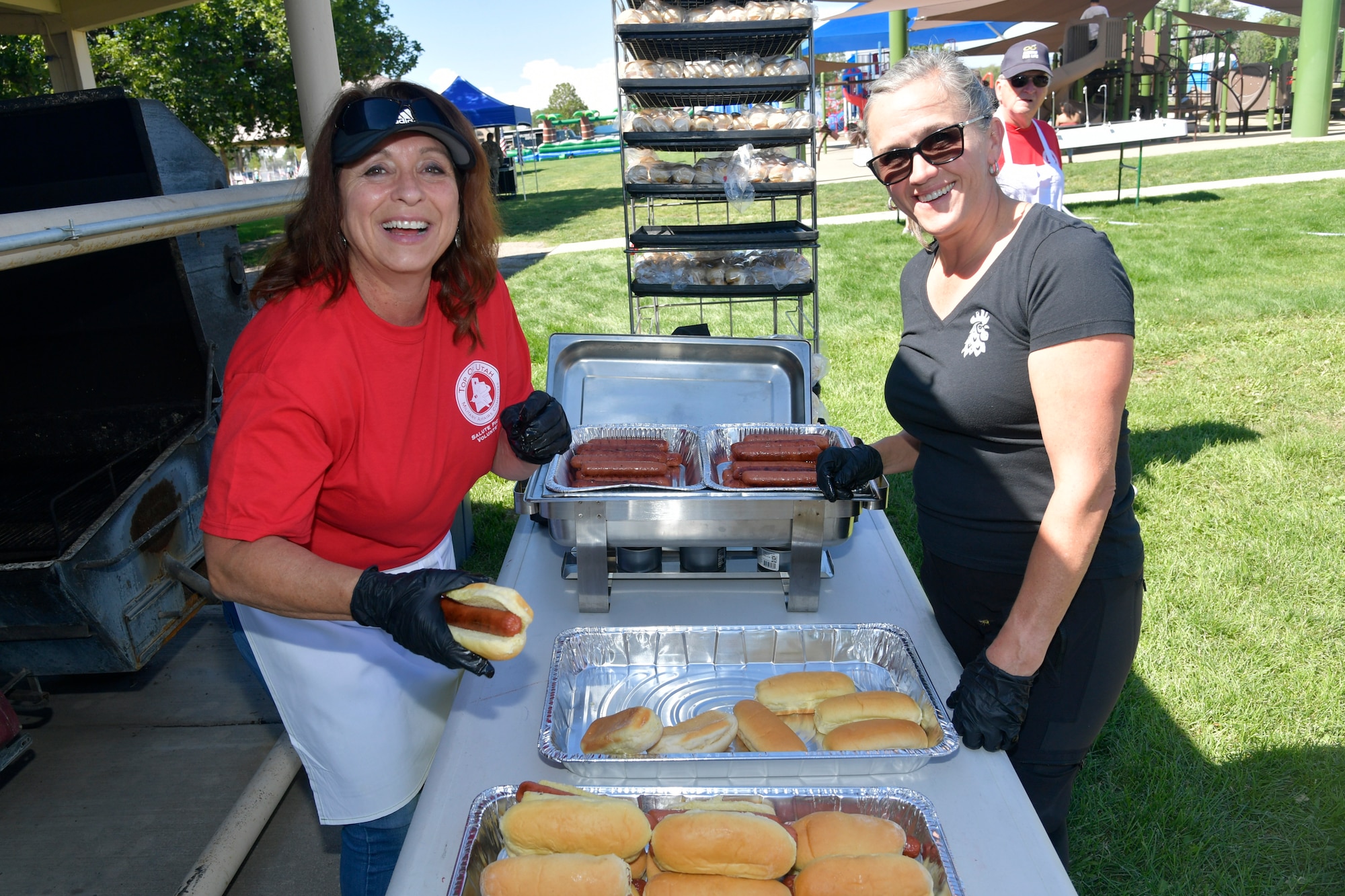 Two volunteers pose for a photo around a table with food on it.