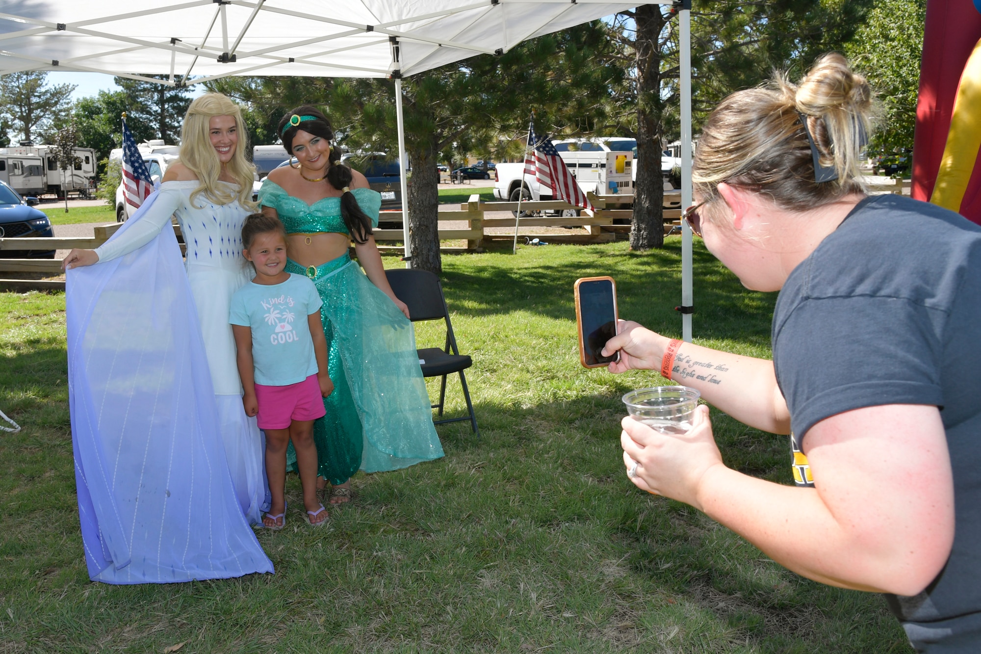 A mom takes a picture of her daughter posing with two princesses.