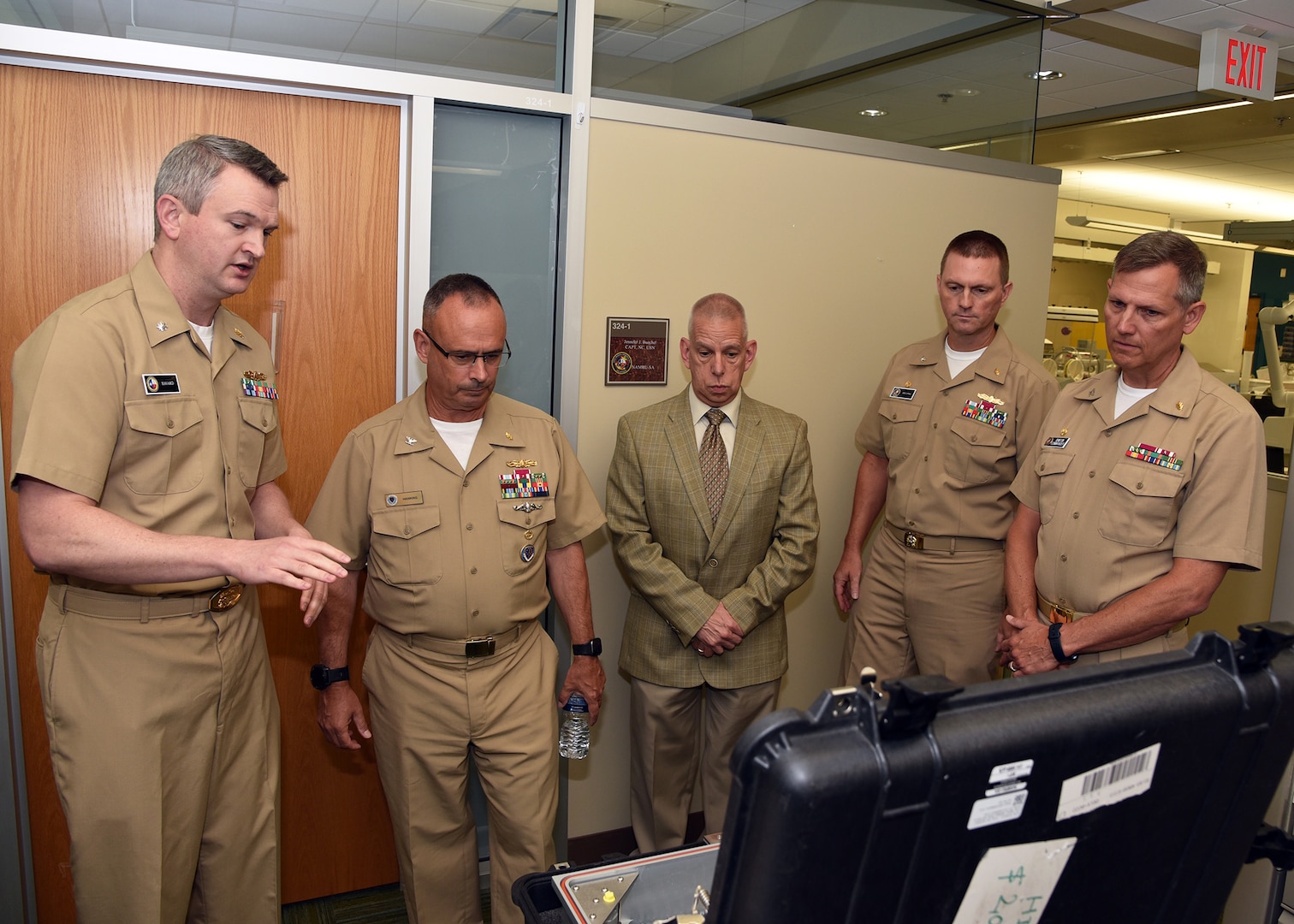 JOINT BASE SAN ANTONIO-FORT SAM HOUSTON – (Aug. 3, 2023) – Cmdr. Drew Havard (left), deputy director of Craniofacial Health and Restorative Medicine (CHRM), Naval Medical Research Unit (NAMRU) San Antonio, joined by Chief Science Director Dr. Sylvain Cardin, Commanding Officer Capt. Gerald DeLong, and Capt. William Deniston, commander, Naval Medical Research Command (NMRC), speaks with Capt. Robert Hawkins, director, J3/5/7, Defense Health Agency (DHA) and director, U.S. Navy Nurse Corps, regarding research and capabilities of the portal ozone sterilizer during a tour of NAMRU San Antonio facilities at the Battlefield Health and Trauma Research Institute. Scientists assigned to CHRM integrate research in the areas of biomaterials, biostatistical analysis, environmental surveillance, epidemiology, infection control, and maxillofacial injury. NAMRU San Antonio’s mission is to conduct gap driven combat casualty care, craniofacial, and directed energy research to improve survival, operational readiness, and safety of Department of Defense (DoD) personnel engaged in routine and expeditionary operations. It is one of the leading research and development laboratories for the U.S. Navy under the DoD and is one of eight subordinate research commands in the global network of laboratories operating under NMRC in Silver Spring, Md. (U.S. Navy photo by Burrell Parmer, NAMRU San Antonio Public Affairs/Released)