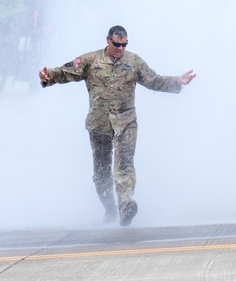 Illinois Army National Guard Chief Warrant Officer 4 Josh Perrott walks through a water cannon salute following the completion of his final flight as an Army aviator Aug. 3. Perrott, who retires Nov. 1, has served 31 years in the Illinois Army National Guard.