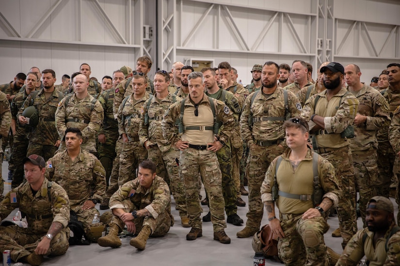 Paratroopers stand together in a large room.