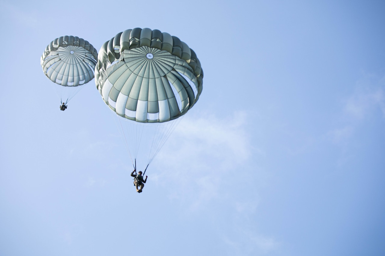 Two paratroopers descend from the sky.