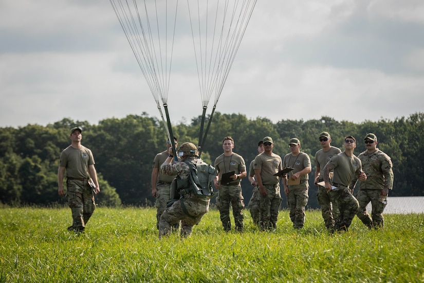 A paratrooper lands in front of a group of people..