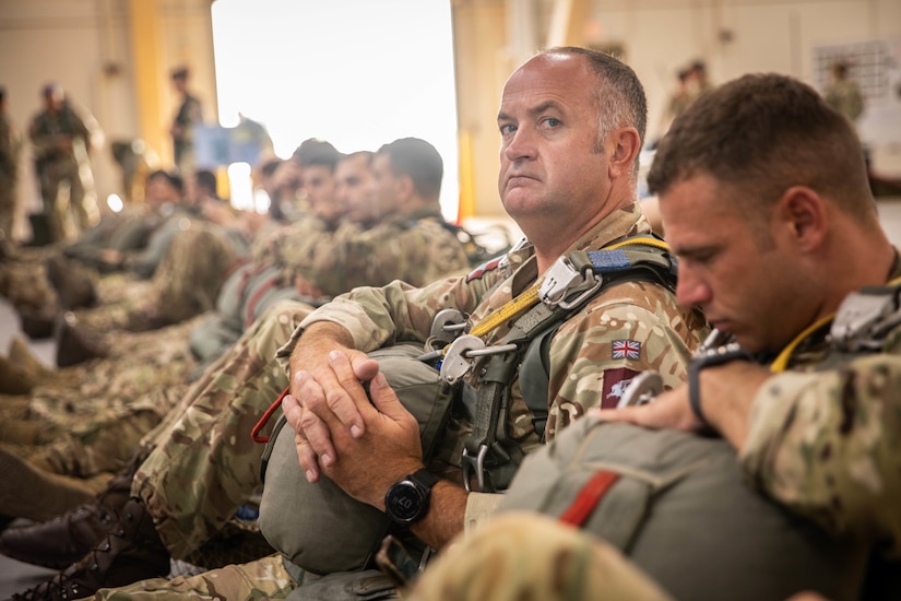 Paratroopers sit in a group with their equipment.