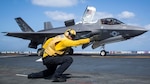 A jet gets ready for take off as an air traffic controller points the way