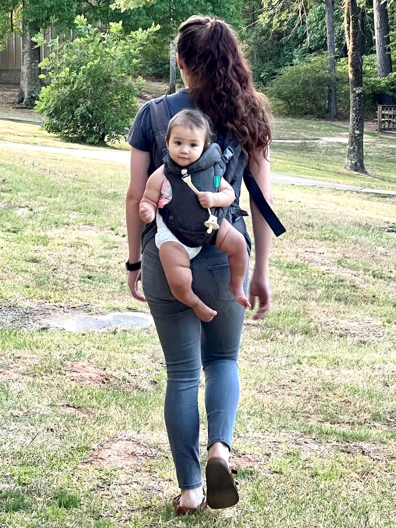 Woman walking away with a baby on her back in a papoose.