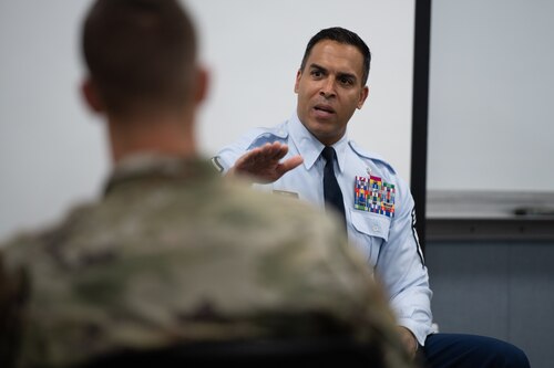 Chief master sergeant in blues uniform speaks to airmen in a classroom setting