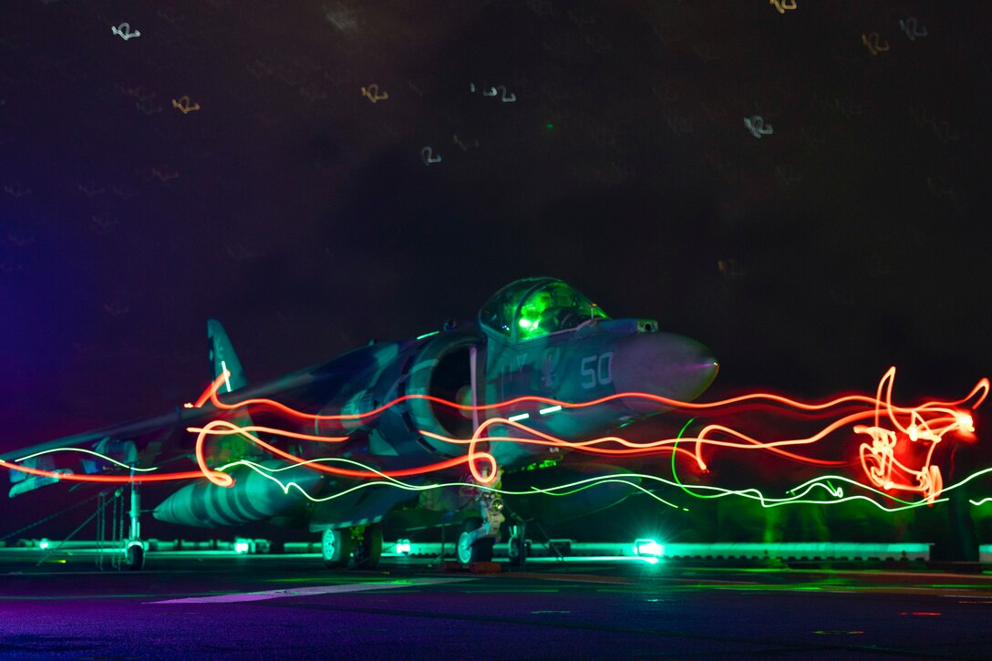 Colorful streaks surround an aircraft preparing to takeoff aboard a ship.
