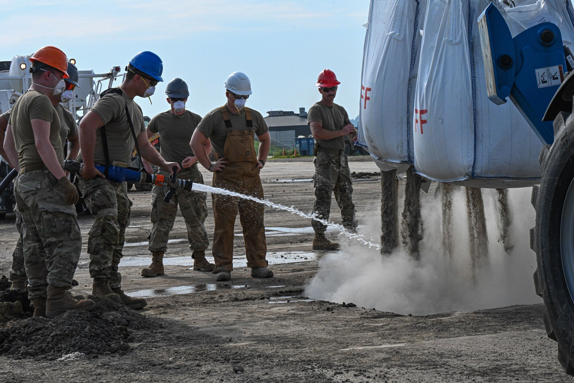 Airmen place concrete on a runway.