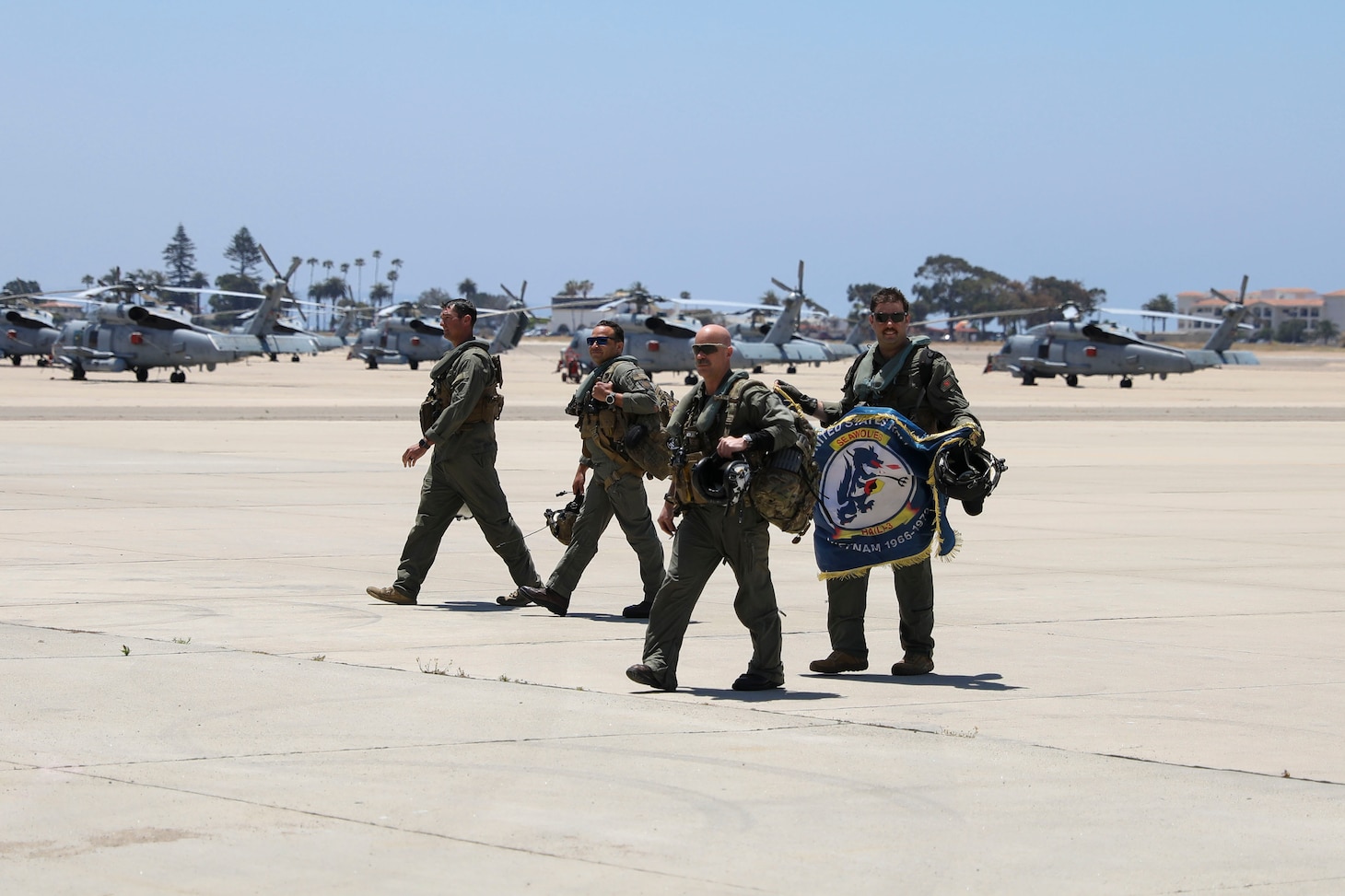Sailors assigned to the "Firehawks" of Helicopter Sea Combat Squadron (HSC) 85 return to the squadron's hangar after the squadron's final flight, carrying the flag of their predecessor squadron, the "Seawolves" of Helicopter Attack Squadron (Light) 3.